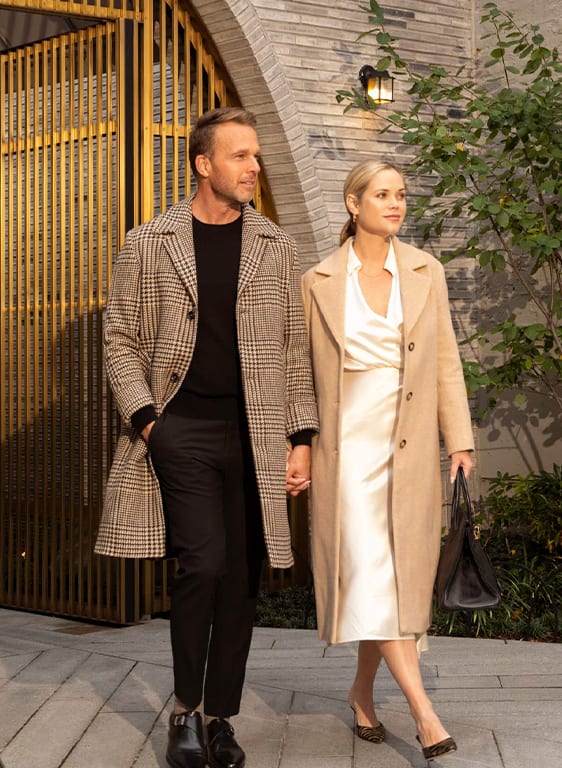 Man and woman holding hands existing front gilded entrance of 180 E 88th Street, luxury condominium in Upper East Side New York City