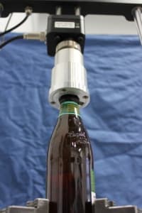 Image of Test Stand with custom adapter holding beer bottle to test torque on capped seal.