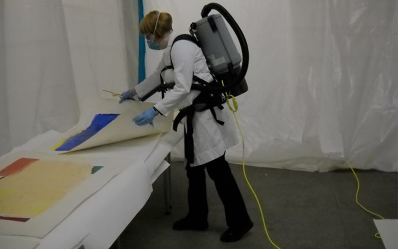 Paintings Conservator Tara Kennedy vacuuming mold off artwork after Hurricane Sandy