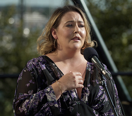 Tracy Lynn Olivera emotionally singing in front of a microphone