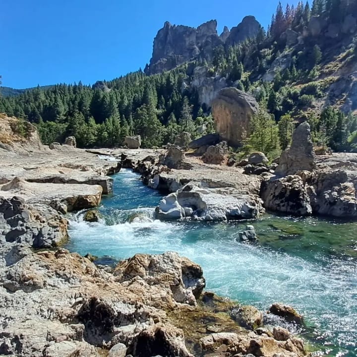Los pozones del Caleufú: agua turquesa entre rocas talladas, con farallones de piedra y bosque detrás