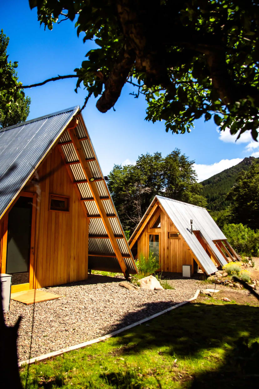 Cabañas A-frame de El Diucón con paneles solares en el techo, rodeadas de bosque en Villa Lago Meliquina