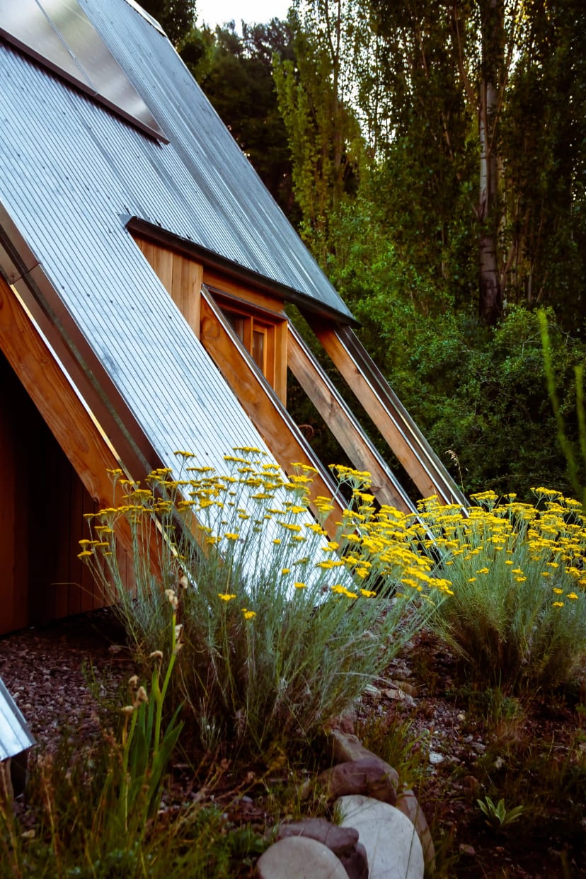 Cabaña A-frame de El Diucón con paneles solares, sendero de piedra y la montaña patagónica de fondo