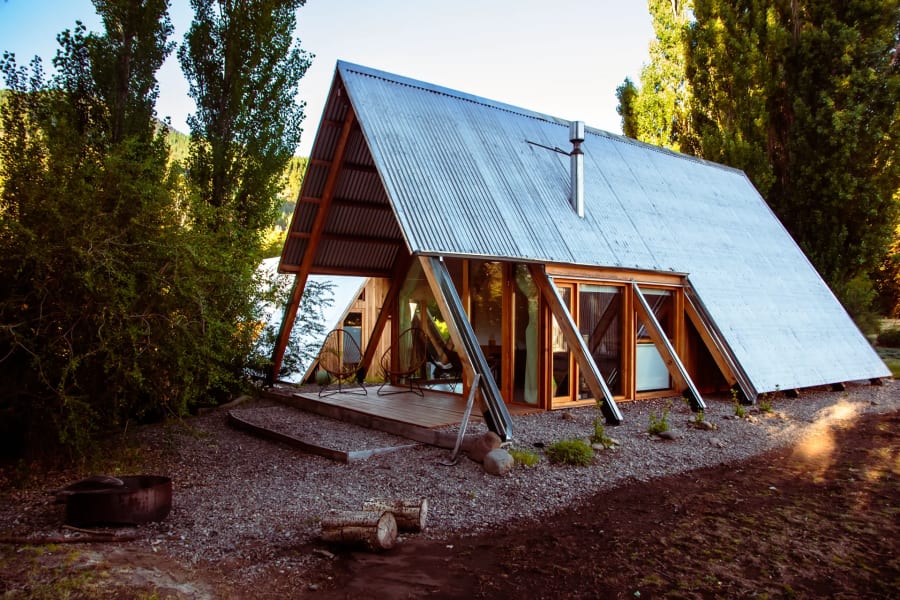 Frente de la cabaña A-frame con la luz dorada del atardecer sobre la madera