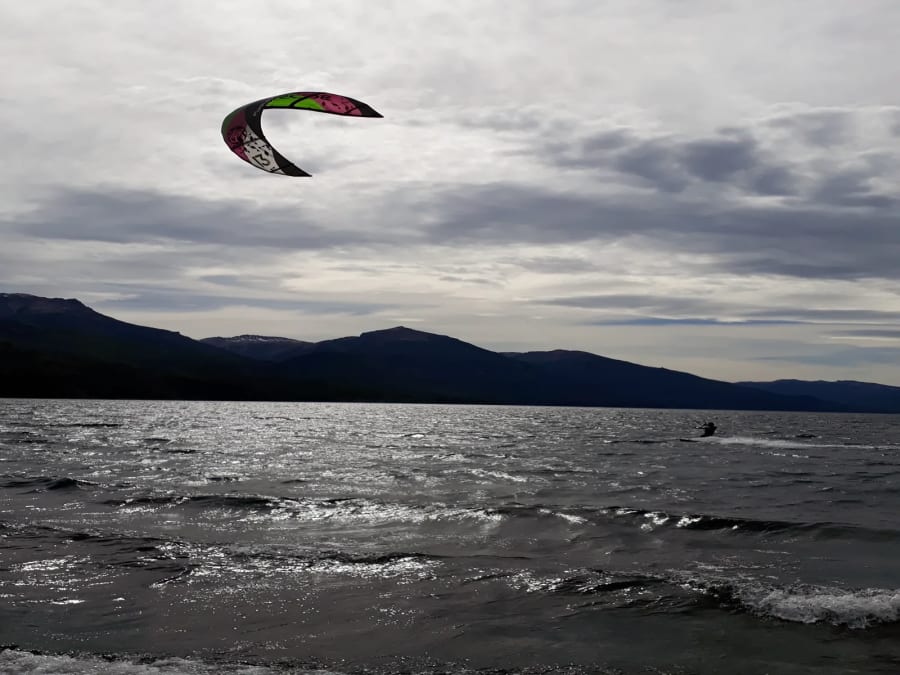 Un kitesurfista navegando sobre el lago Meliquina con los cerros de fondo