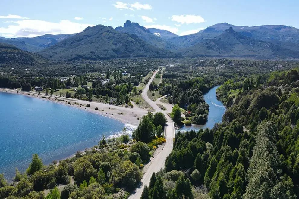Vista aérea de la costa del lago Meliquina, la salida del río y el camino que entra a la villa entre los cerros