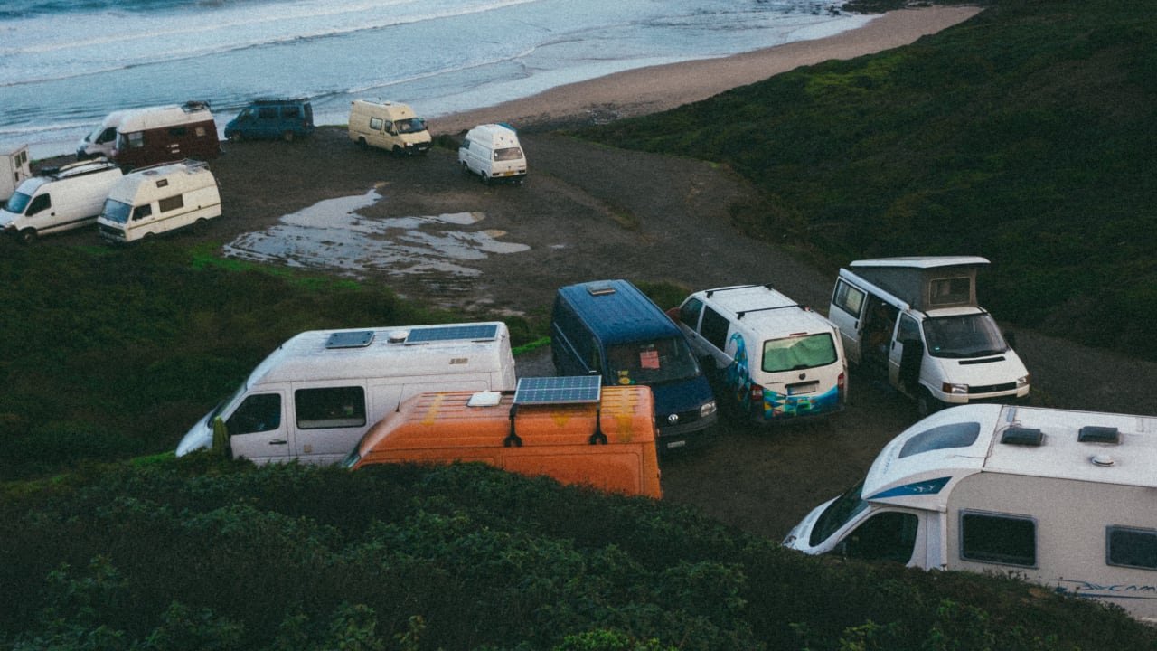 Wohnmobile mit Solarzellen auf dem Dach, die am Strand geparkt sind.