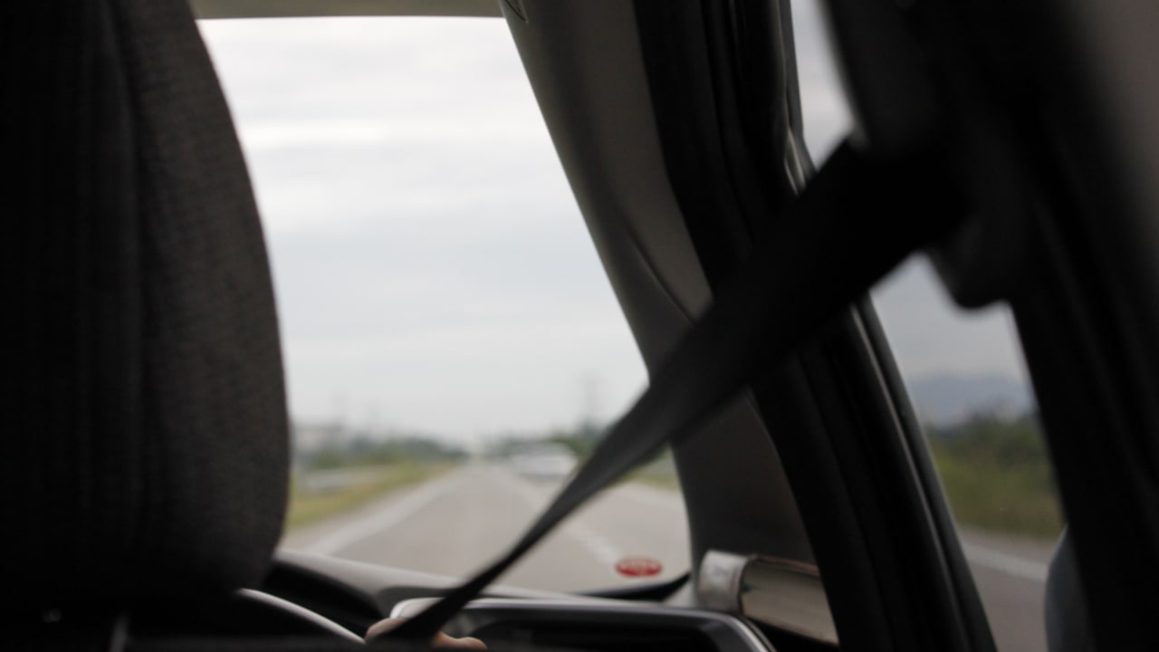 A person driving a car, the seat belt is in focus