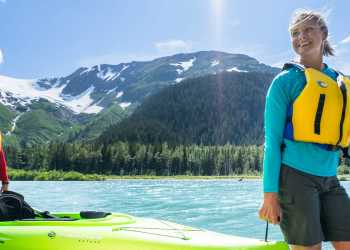 A couple carries a kayak along the shore of Explorer Lake.