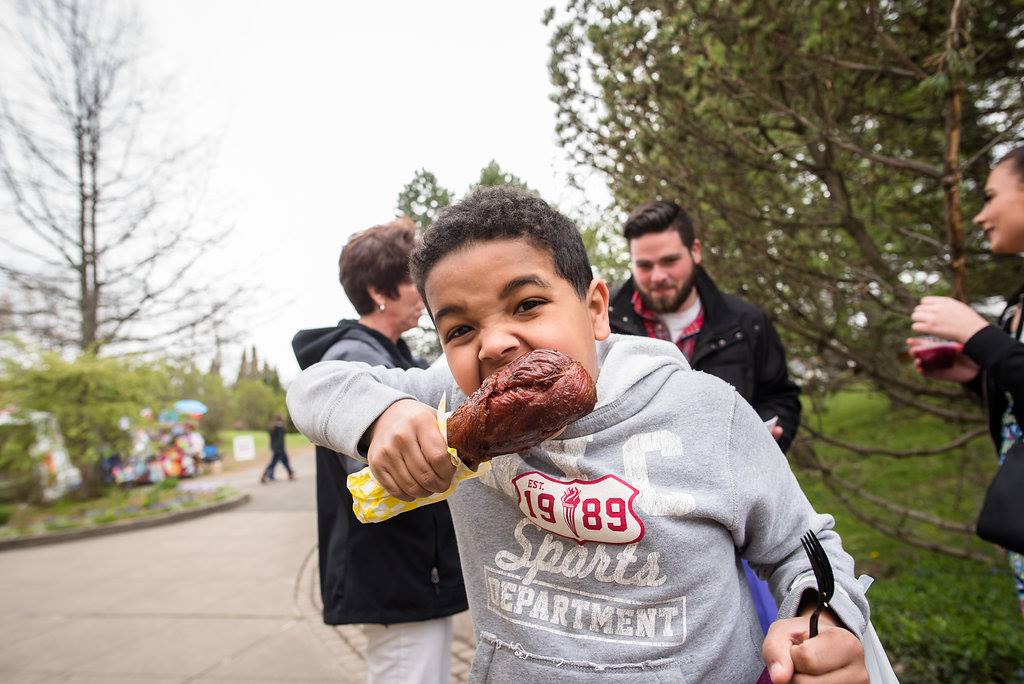 boys bites into a turkey leg at the Rochester Lilac Festival