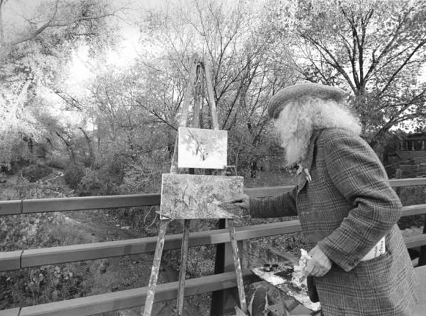 Tommy Macaione painting on a bridge over the Santa Fe River. (Photo courtesy of The Palace of the Governors Photo Archives, Negative HP.2014.14.1739)