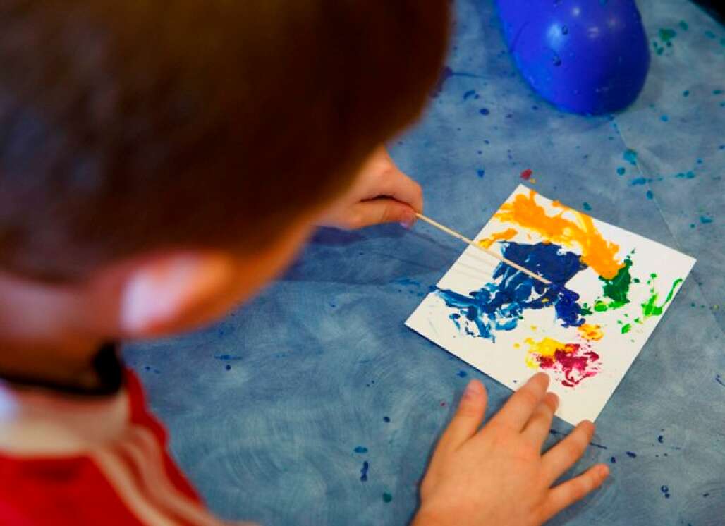 A kid creating a piece of art with crayola colors