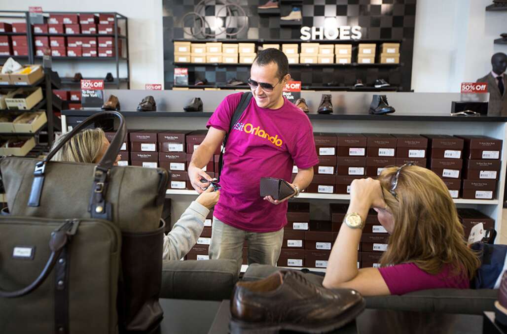 Brazilian tour guides and meeting planners show of each other's purchases at the new Saks Off 5th at the Orlando Premium Outlets.