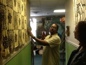 Dr. John Aden shows mud cloths to a visitor.