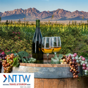 bottle of wine and two win glasses with a vineyard in background