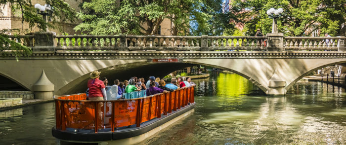 Passengers on a River Walk barge under a bridge