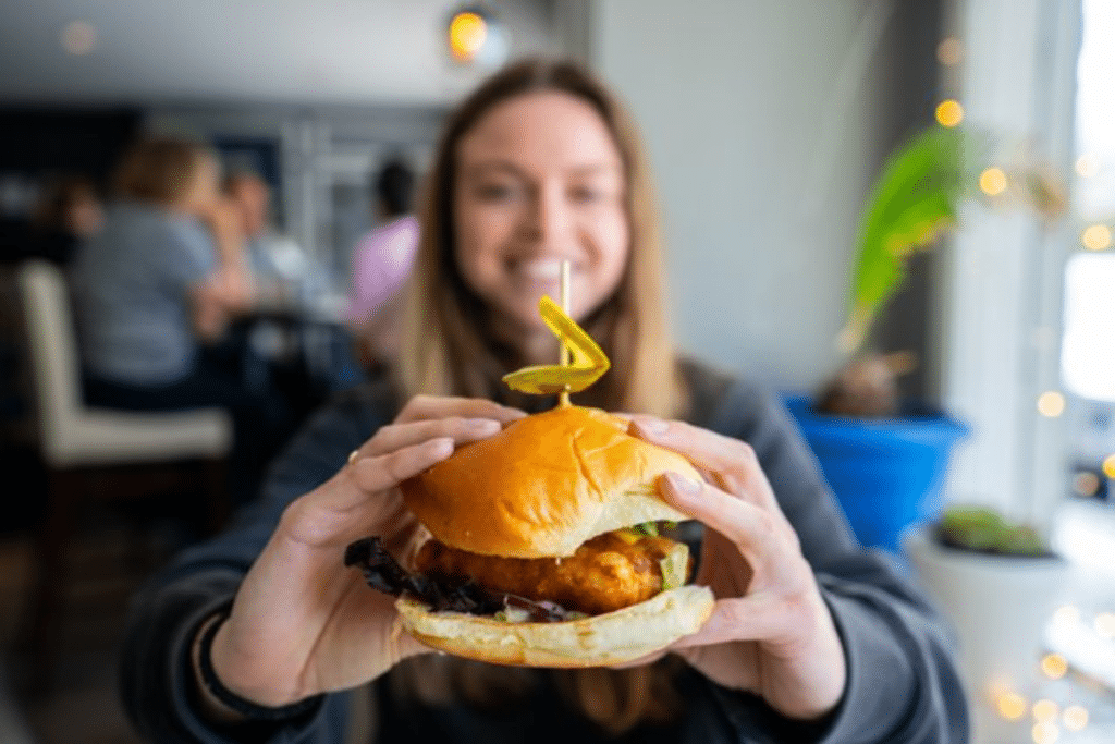 A woman holds up a top notch burger