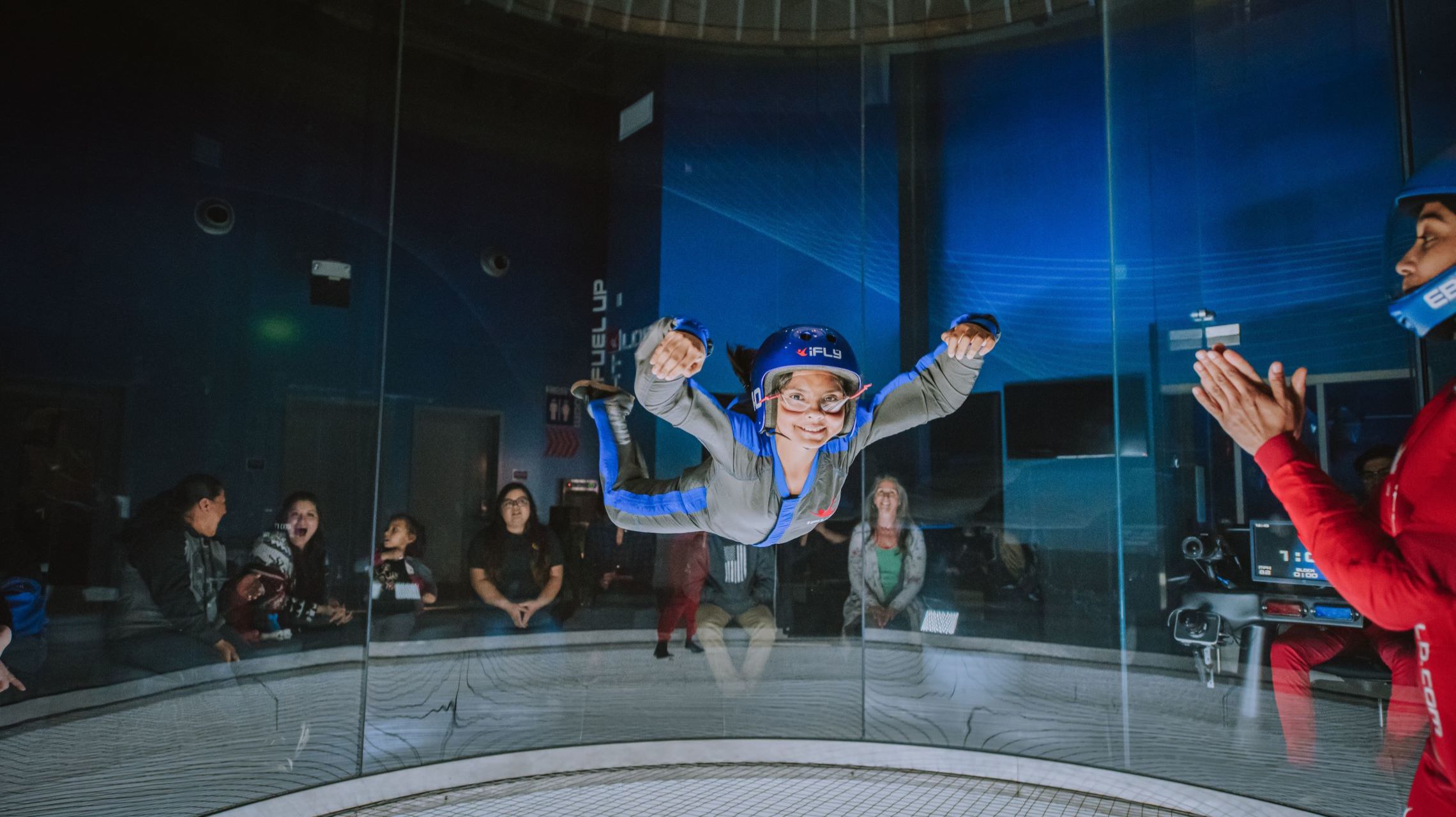 spectators watch child as they are indoor skydiving