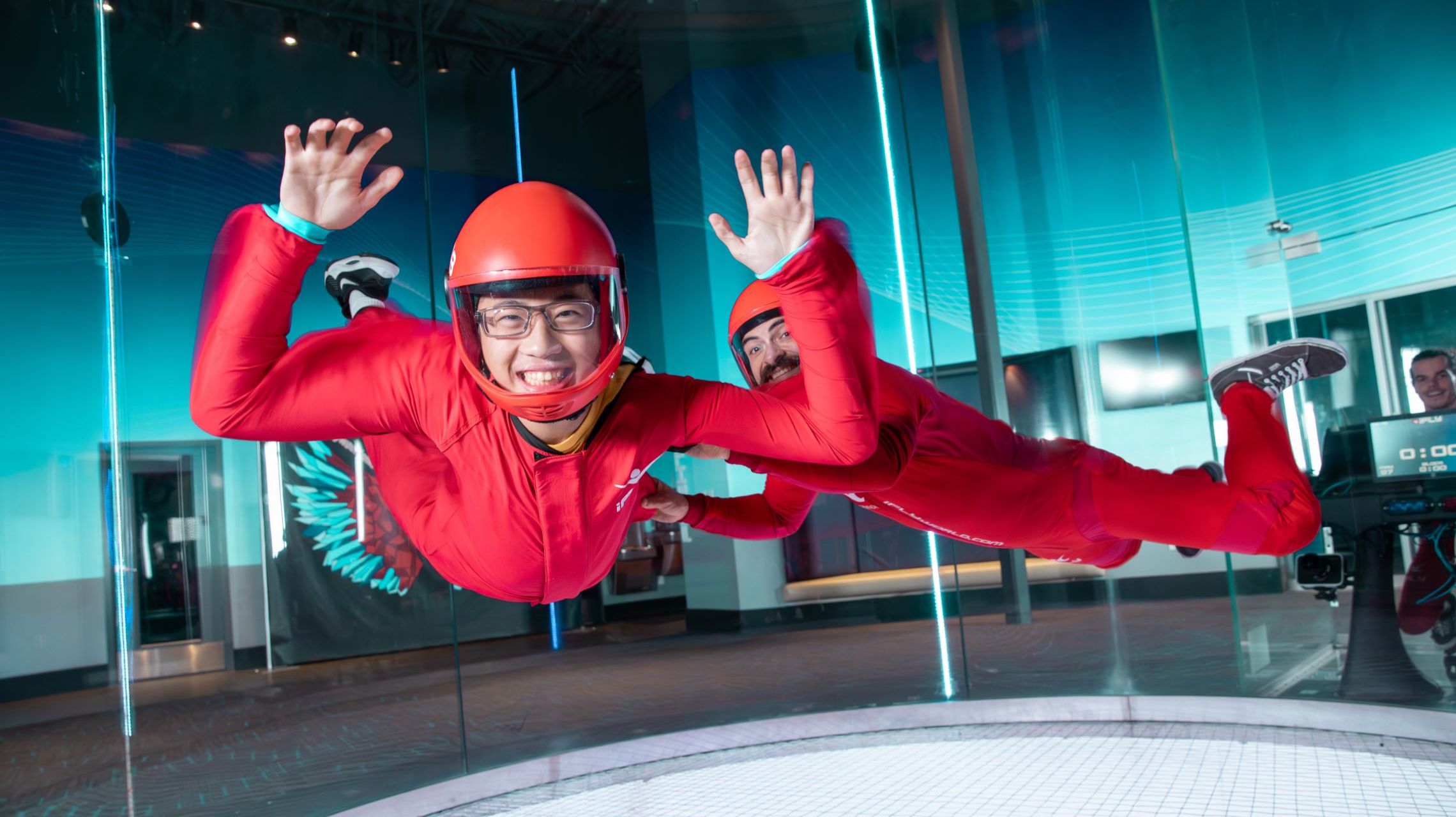 instructor assists flyer inside tunnel at indoor skydiving facility