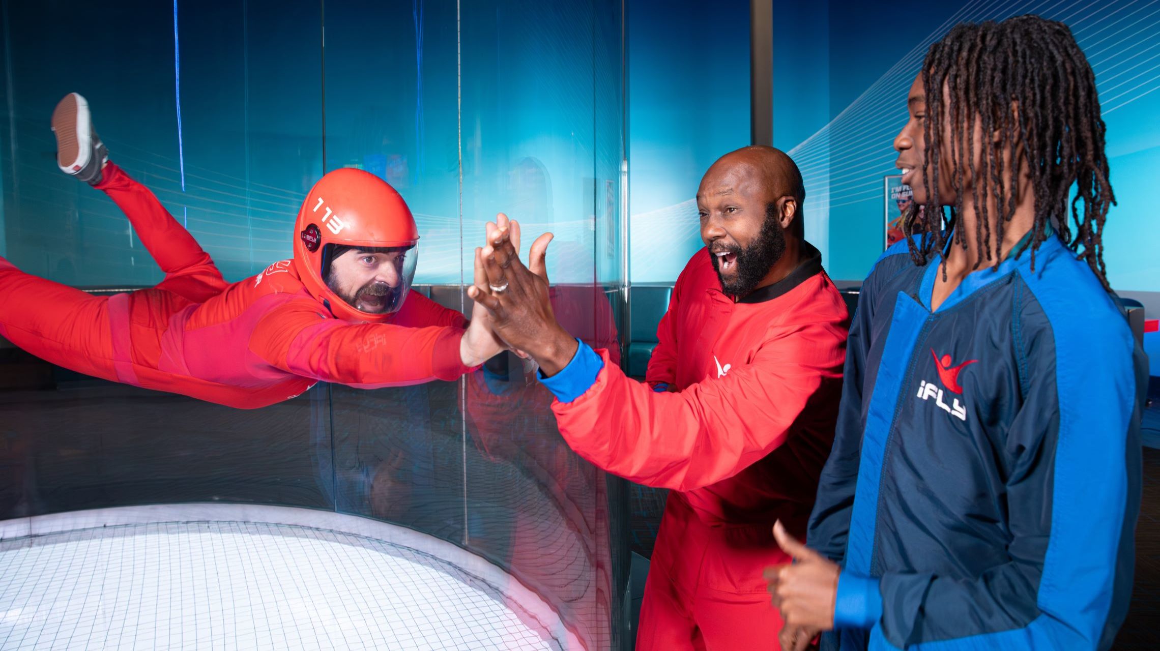 indoor skydiver and spectator high five through wind tunnel glass