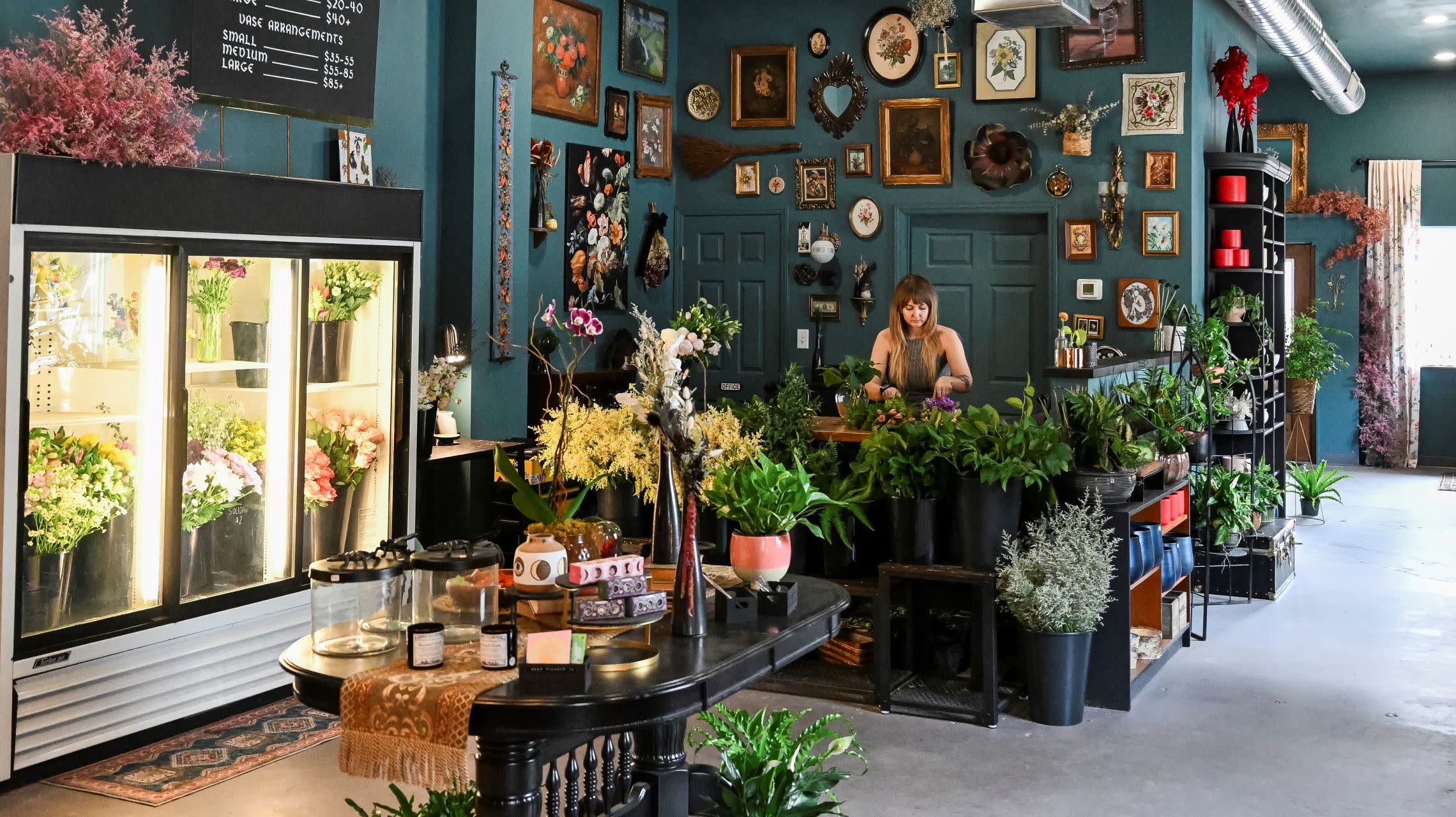 owner works behind the counter of local floral shop filled with flowers and plants