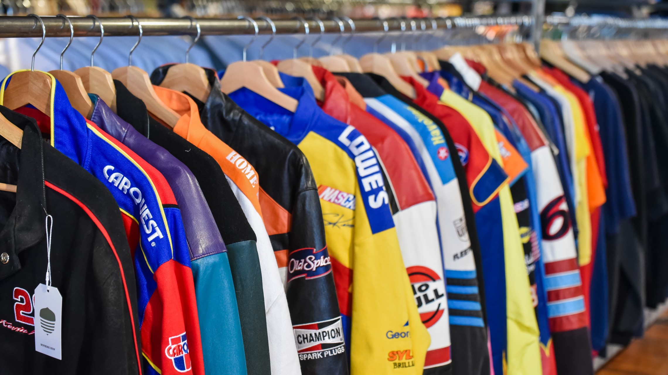 large selection of colorful motorsports jackets on rack inside vintage clothing store