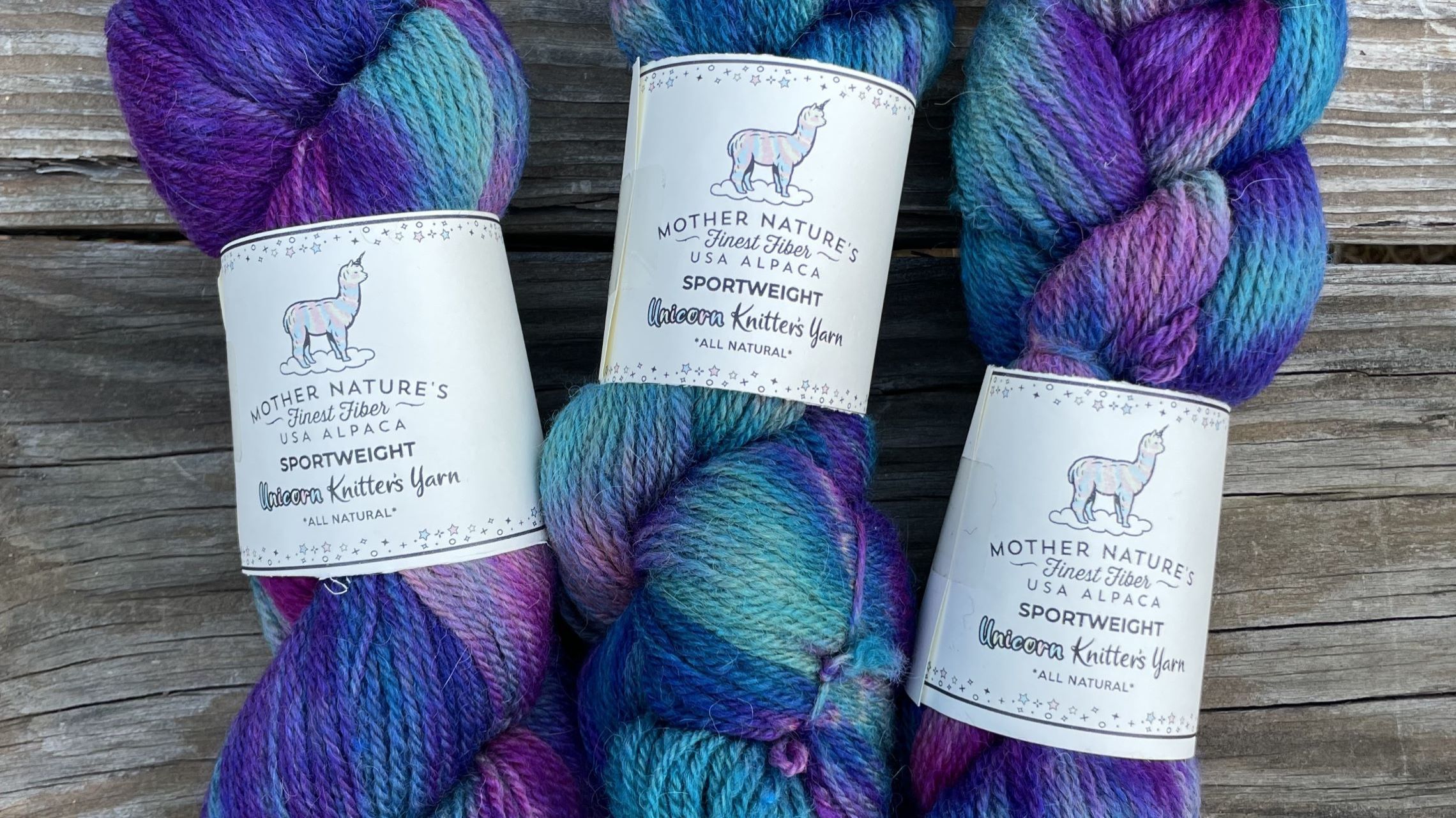 three bundles of colorful blue, purple and magenta knitting yarn made from alpaca fibers