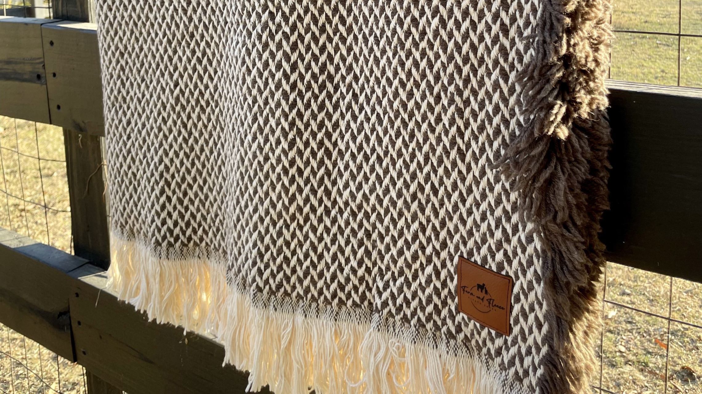 a blanket made from alpaca wool laying over a fence