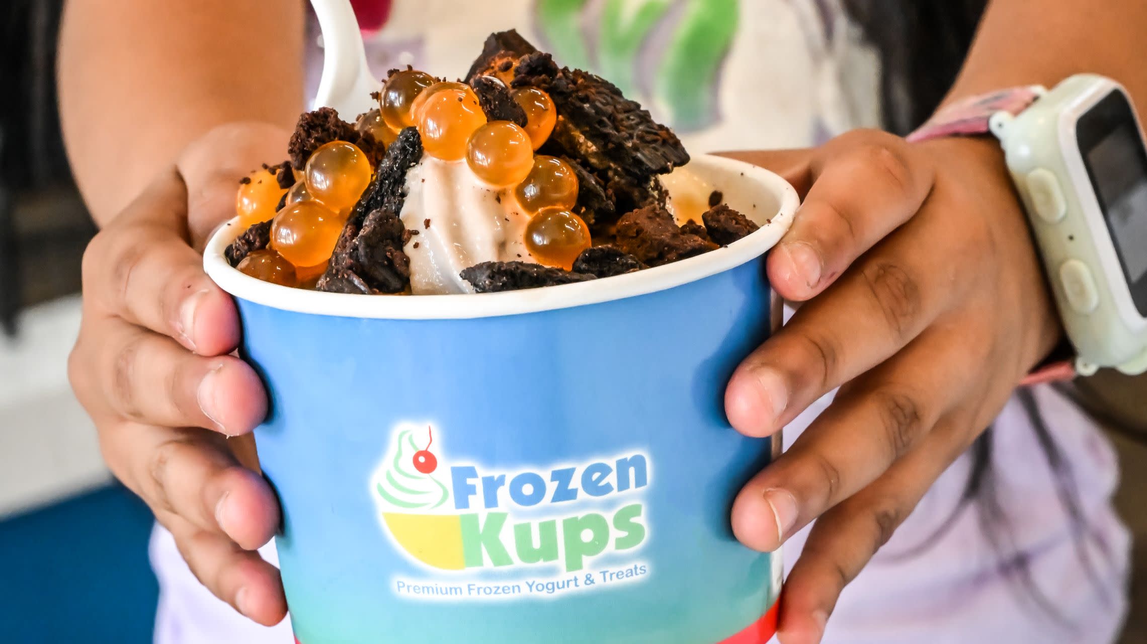 girl holding cup of frozen yogurt