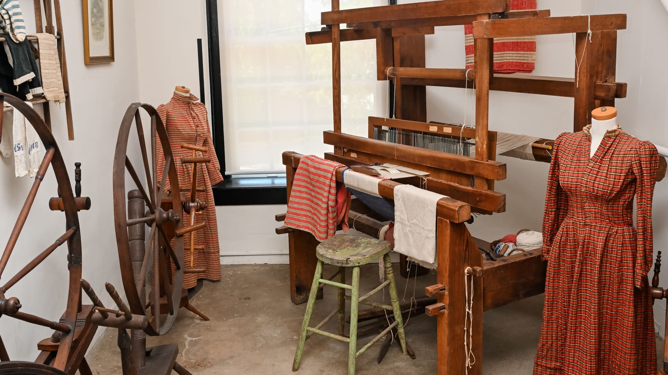 dresses and weaving tools on display inside museum