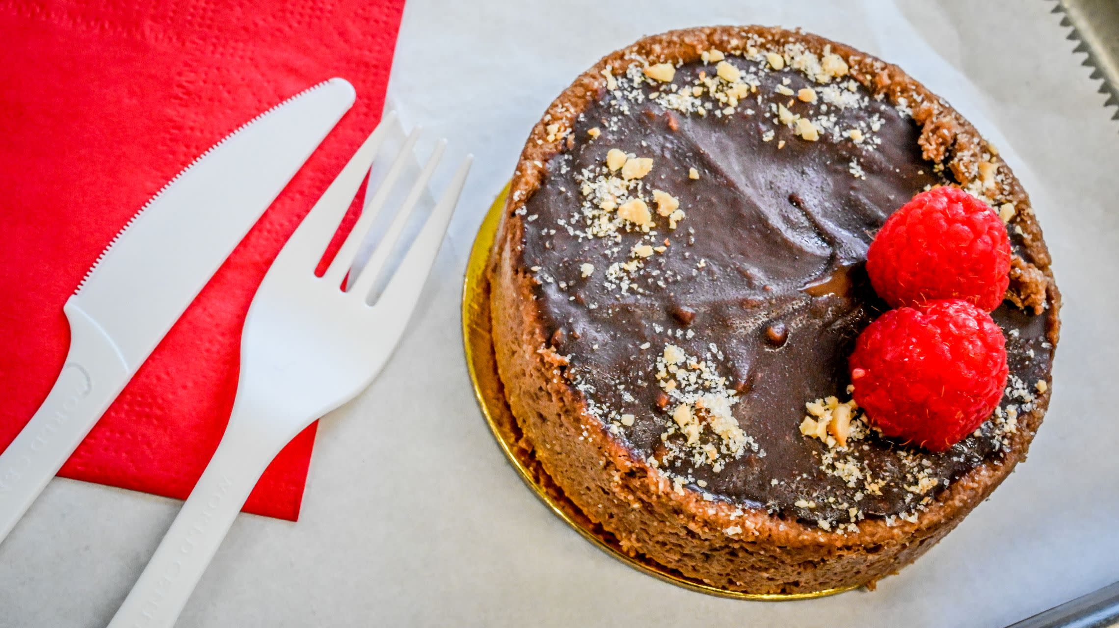 chocolate tart with raspberries on tray with fork and knife