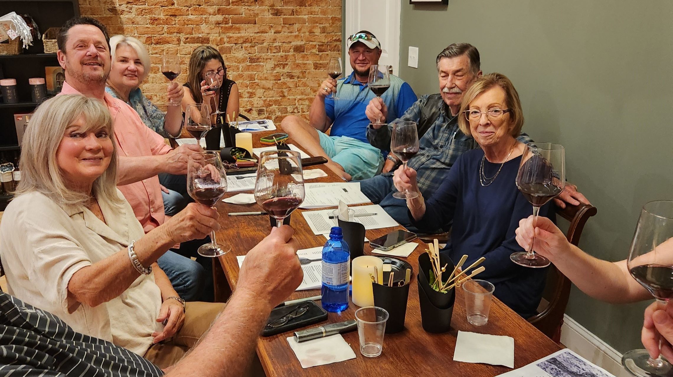 group sitting at table toasts wine glasses