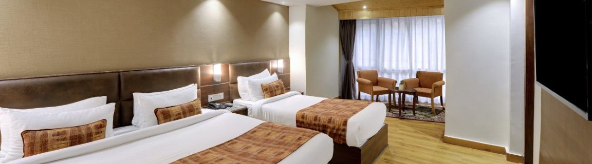 An image of a room with a queen size bed and a single bed with TV and minimal decoration - Sumitel Vista TV Tower