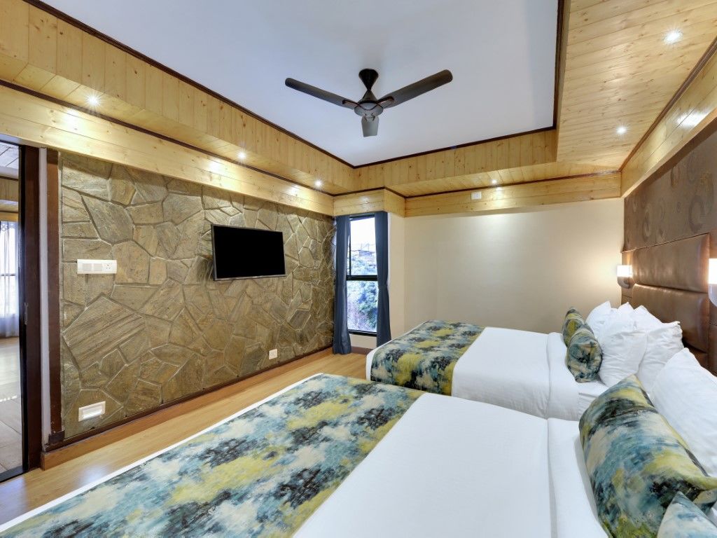 An image of Sumitel Queensyard premium room with king size bed, tv, ceiling fan, and minimal decoration