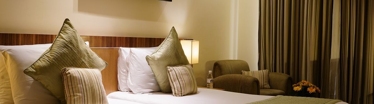 Standard Room featuring twin beds with green duvets and pillows at Shervani Nehru Place, New Delhi