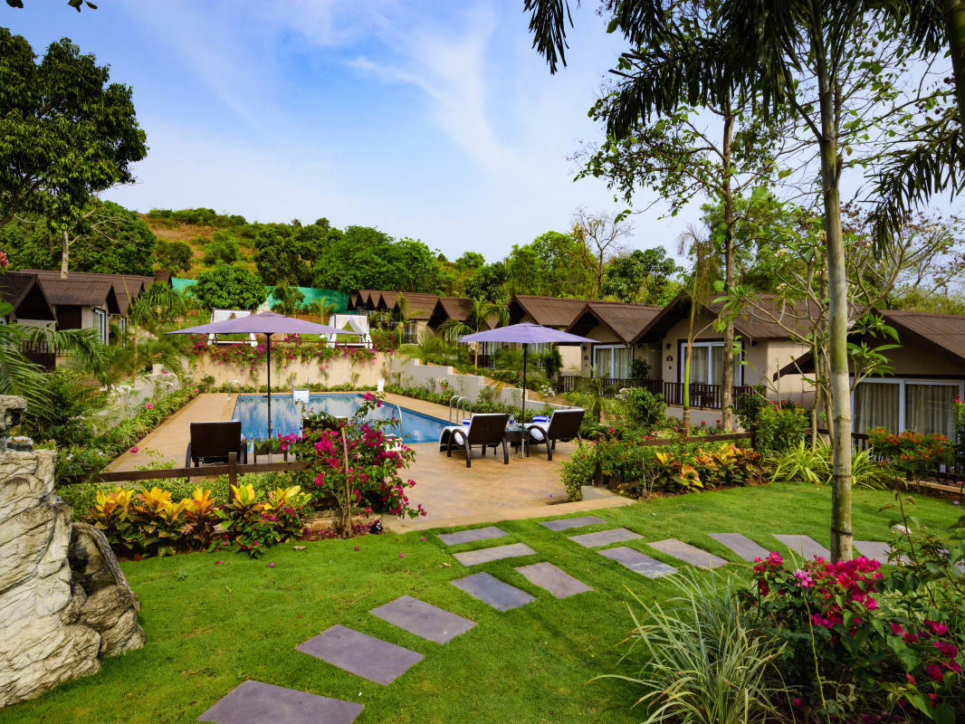 Garden with blooming flowers and cottages at Stone Wood Resorts in Mandrem