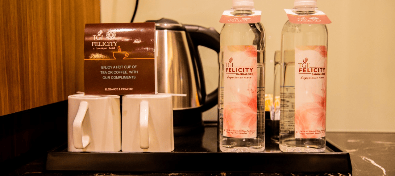 Tray filled with two water bottle, cups and a kettle at TGI Felicity, Bangalore