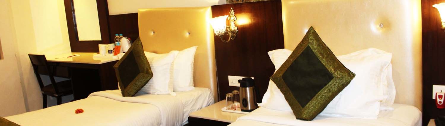 A cosy hotel room with two single beds, beige headboards and a work desk - TGI Apple Inn, Jaipur 