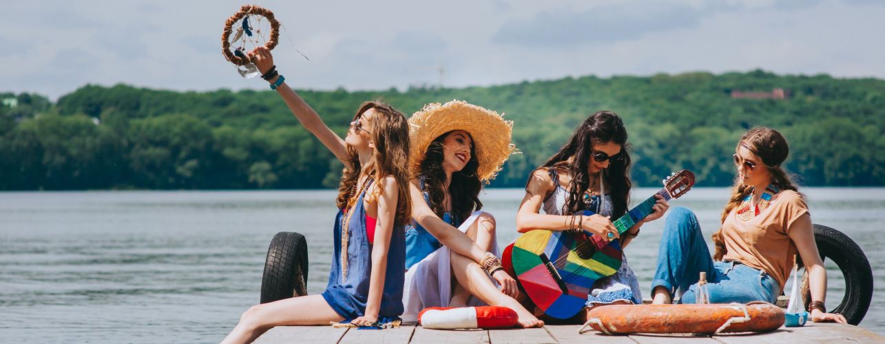 a group of women sun bathing and one girl playing the guitar with the backdrop of a lake - Caravela Beach Resort, Goa