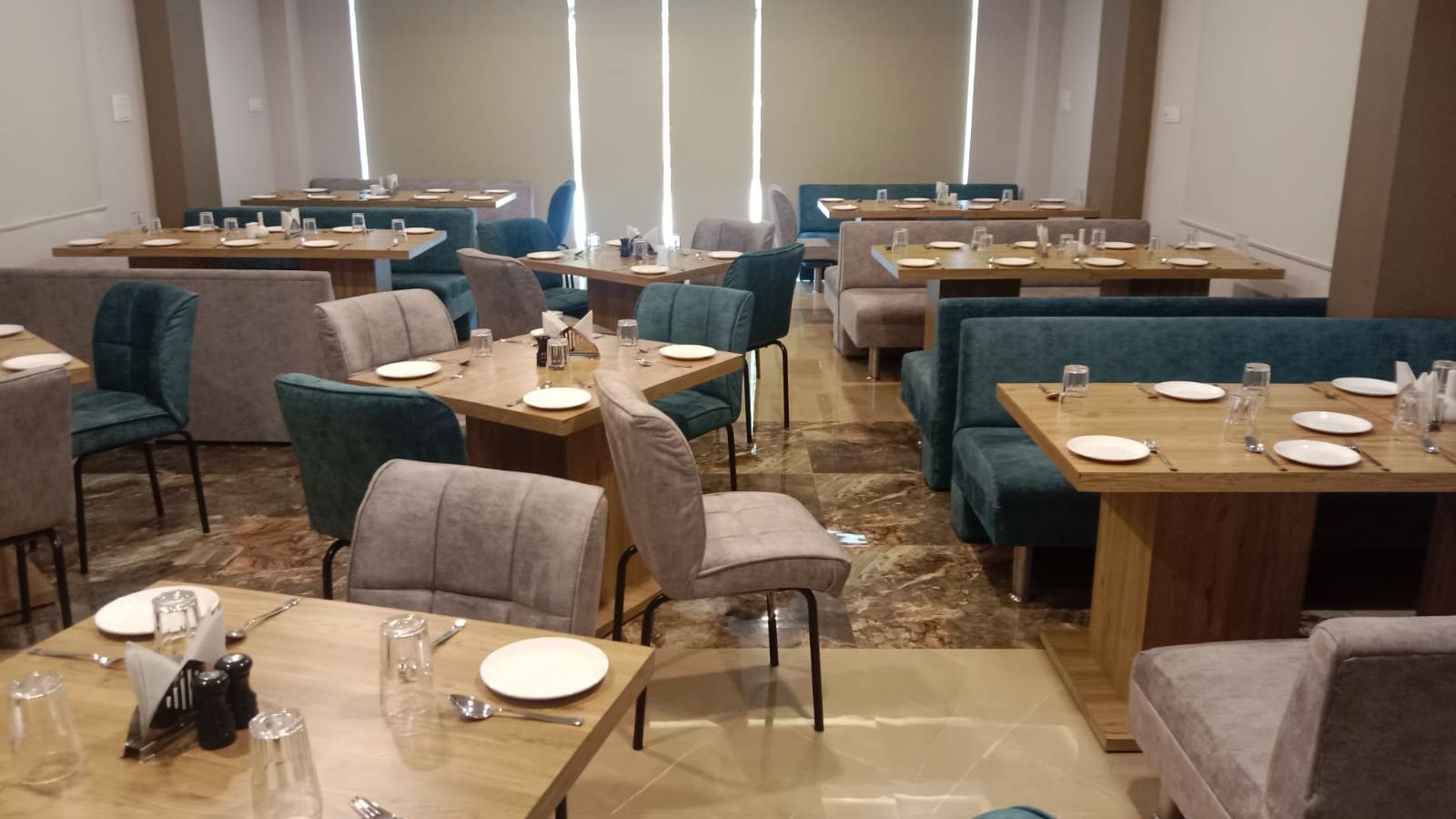 Dining area with cutlery and plates arranged on the table at Hotel Mumbai House, Indore