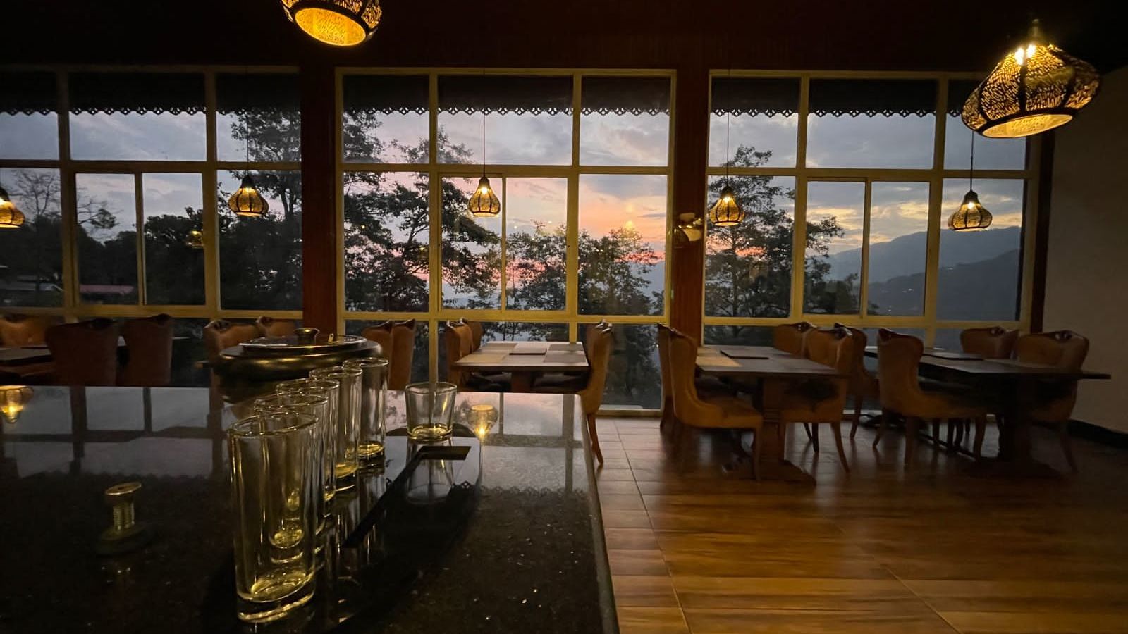 Overview of the Restaurant with seating arrangements and large windows with a view - Sumitel Gangtok lz0l4p