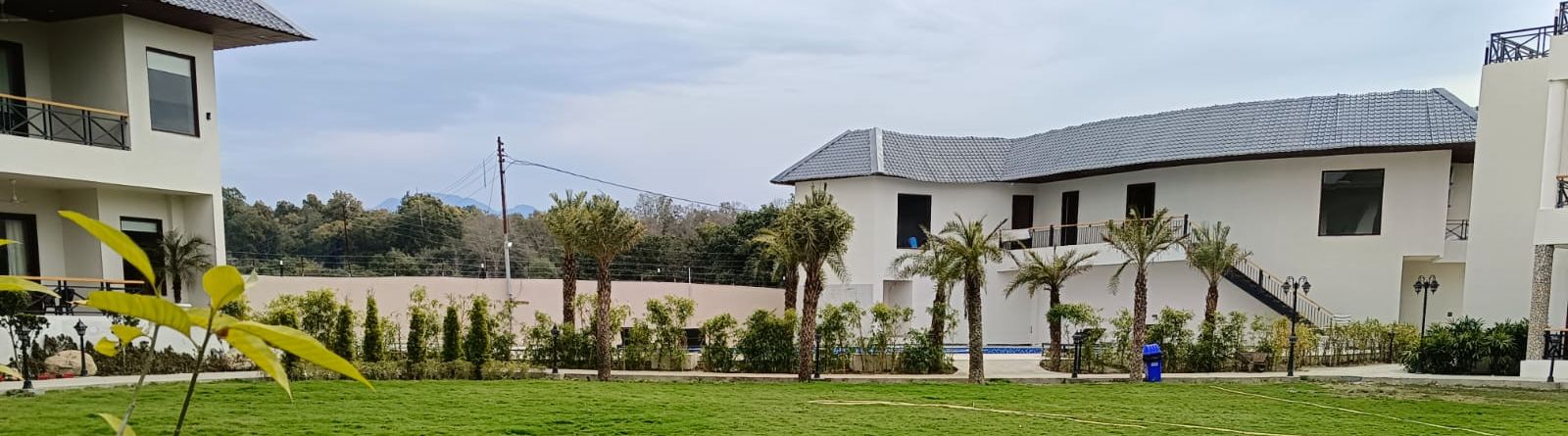 Lawn area of with green foliage and property beside -Shervani Pebbles & Pines, Corbett