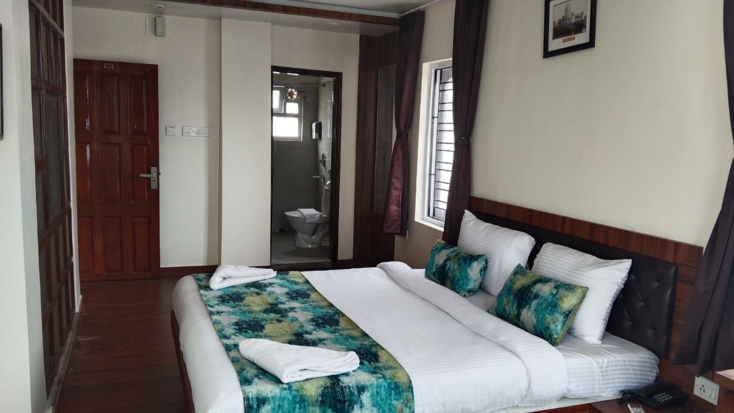 A double bed with towels kept on it inside the Deluxe room - Ecotel Kolkata