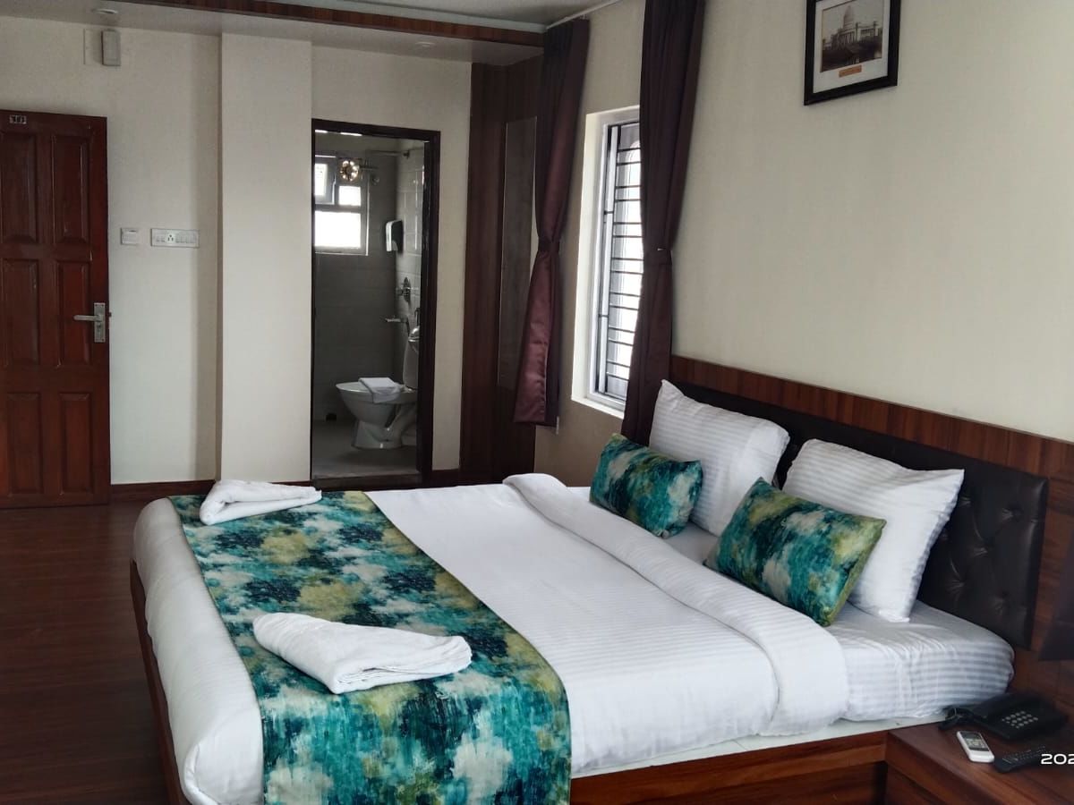 A double bed with towels kept on it inside the Deluxe room - Ecotel Kolkata