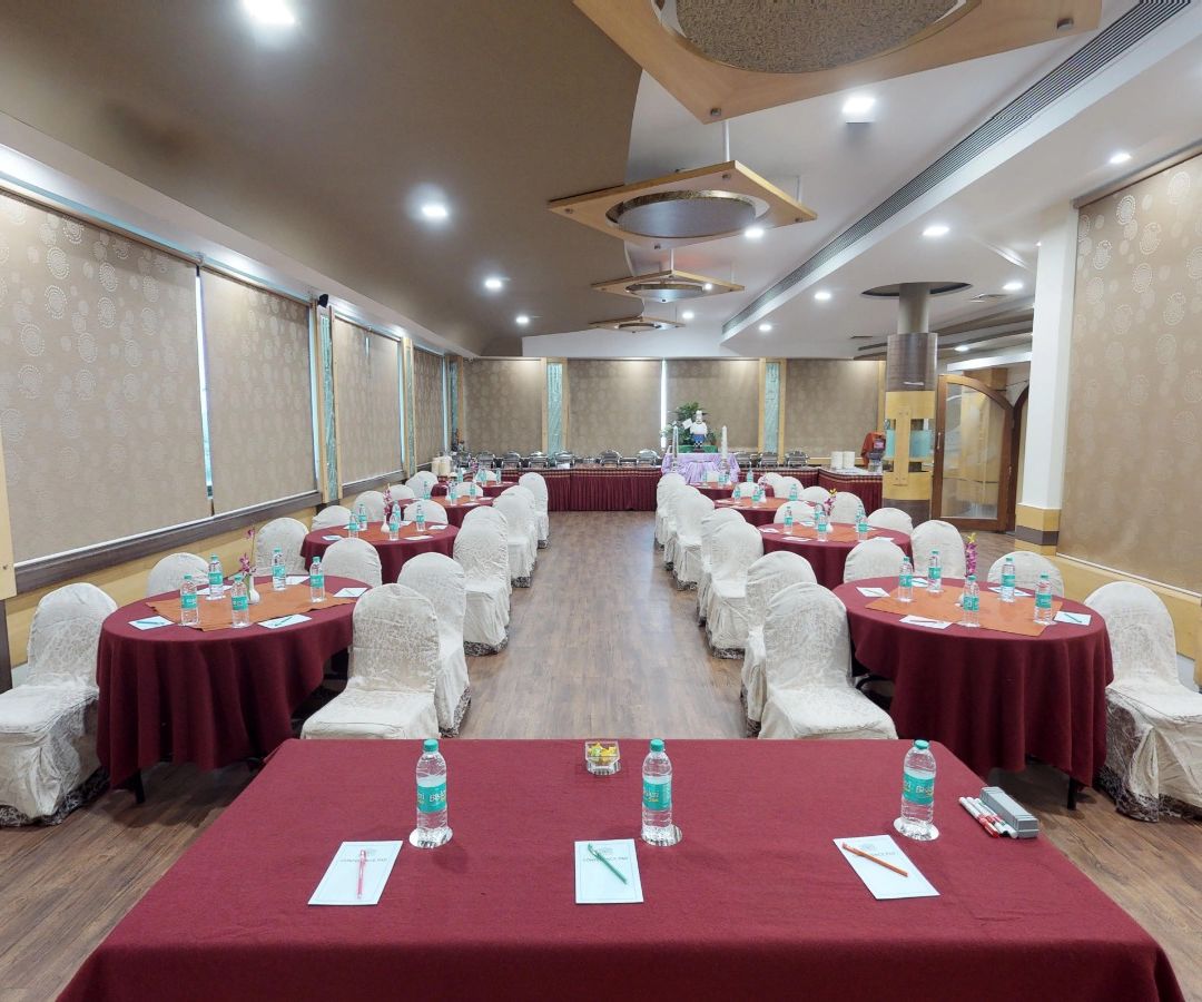 view from the stage of a well lit conference hall setup with designated tables and chairs