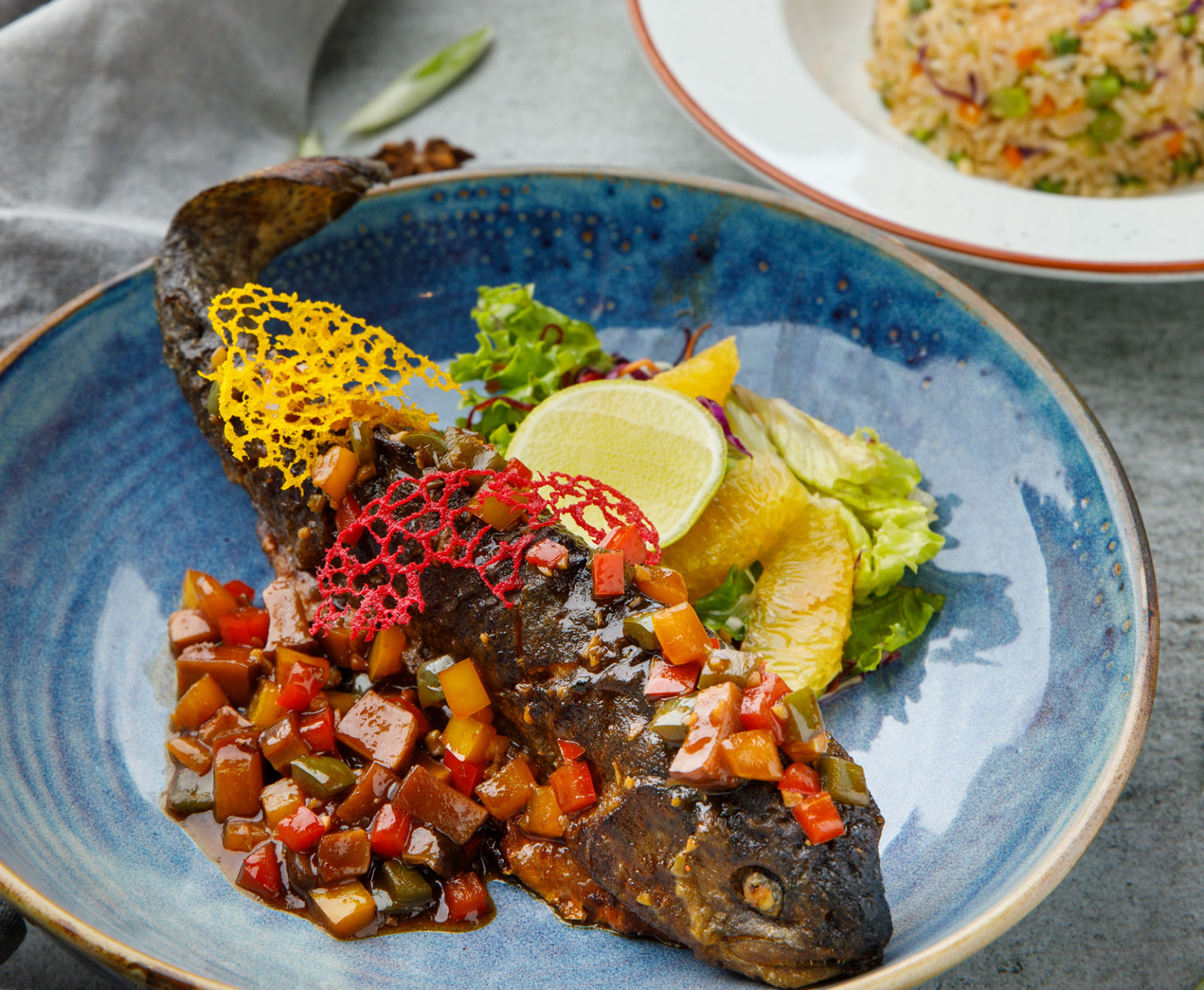 Gourmet plated fish dish with a side of vegetables and rice.