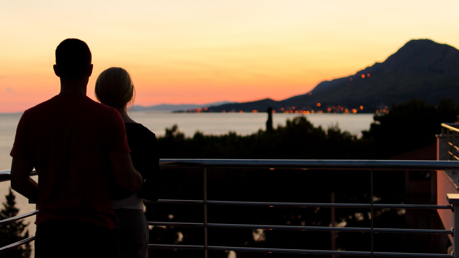 An image showcasing a stunning view of the sea from the balcony of a luxurious room with a couple standing near the balcony 