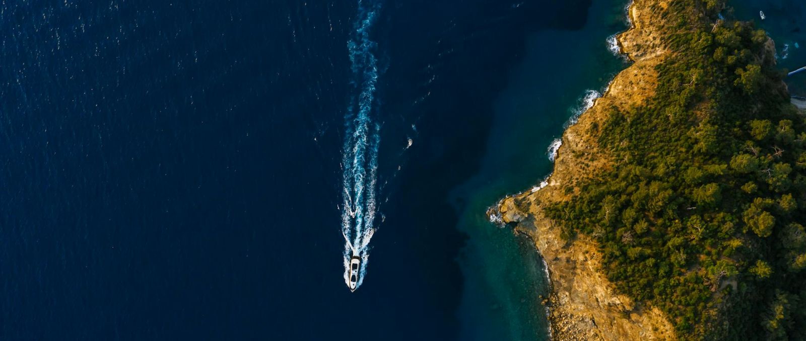 an island and the sea with a speed boat passing by