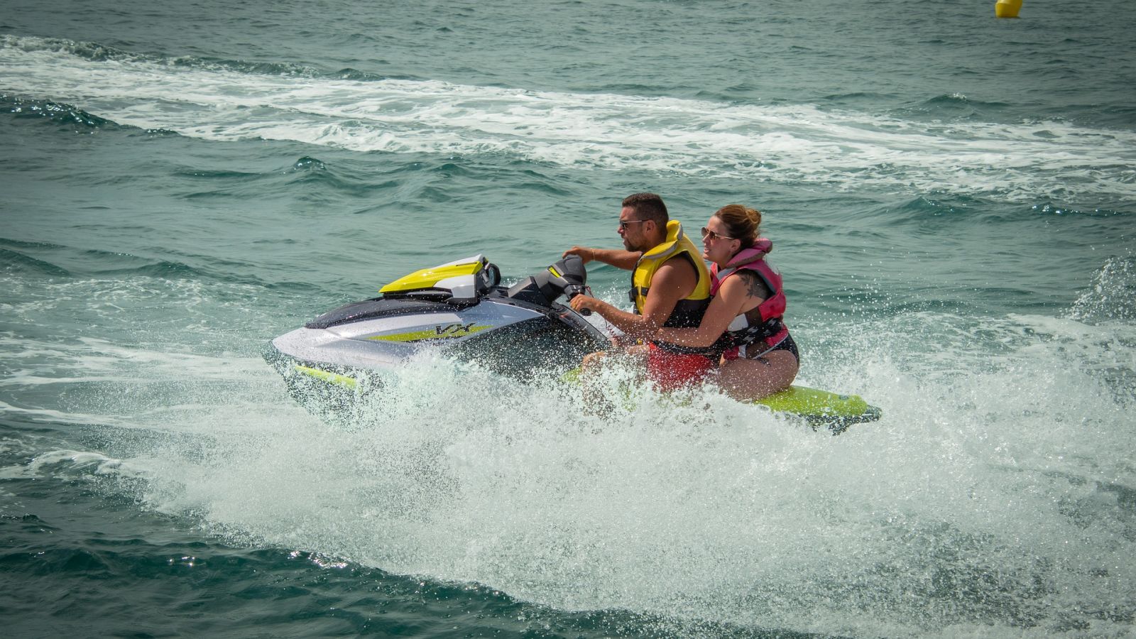 Couple Jet skiing in a beach with waves next to them