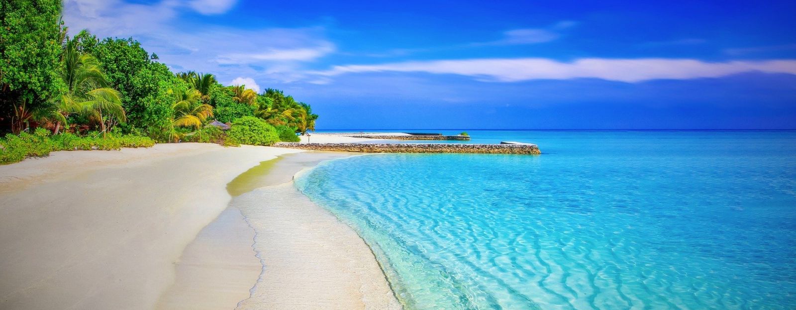 A secluded beach with turquoise water and trees on the side 